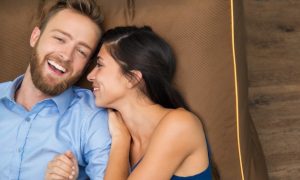 sonriente-joven-pareja-disfrutando-acostado-en-el-sofa_1262-1178