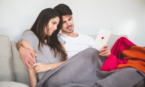 pareja-sonriente-mirando-una-postal-con-un-corazon_23-2147596035