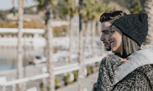 pareja-joven-abrazando-enfrente-de-palmeras_23-2147732037